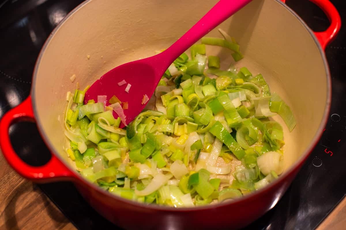 Sautéed leeks in a large pot on a stovetop.