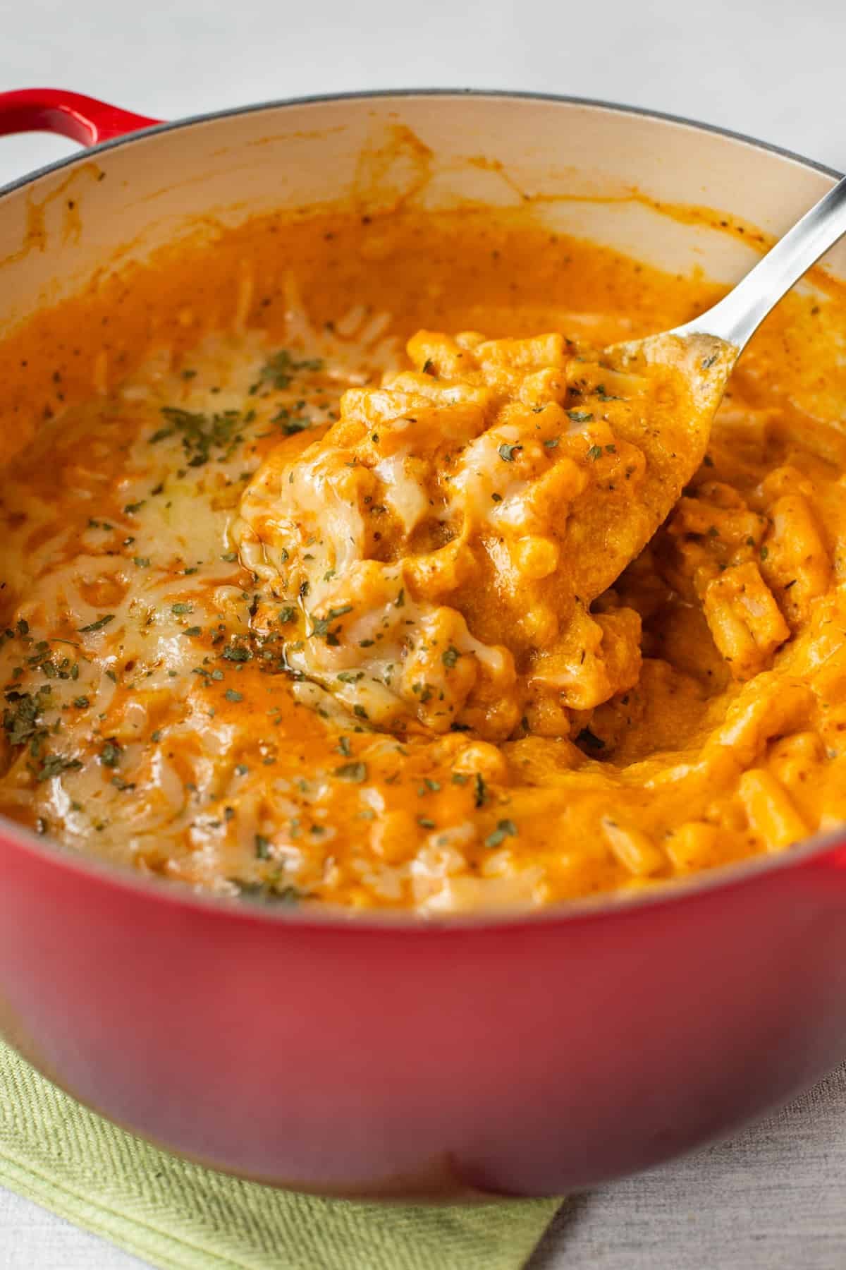 A large spoon taking a scoop of creamy pumpkin mac and cheese.