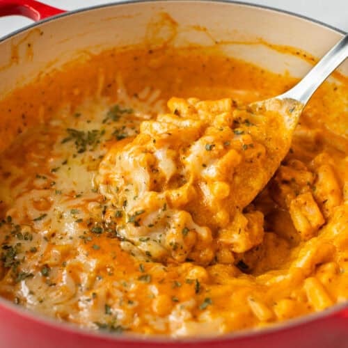 A large spoon taking a scoop of pumpkin mac and cheese.