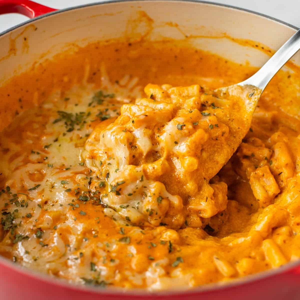 A large spoon taking a scoop of pumpkin mac and cheese.
