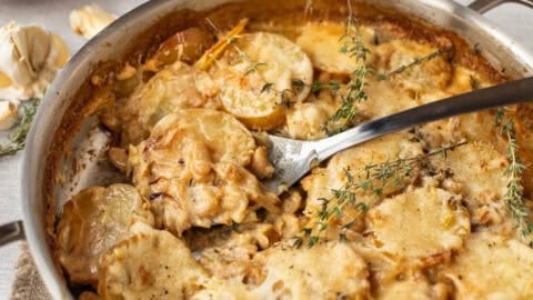 Creamy French onion potato bake in a pan with a large spoon.
