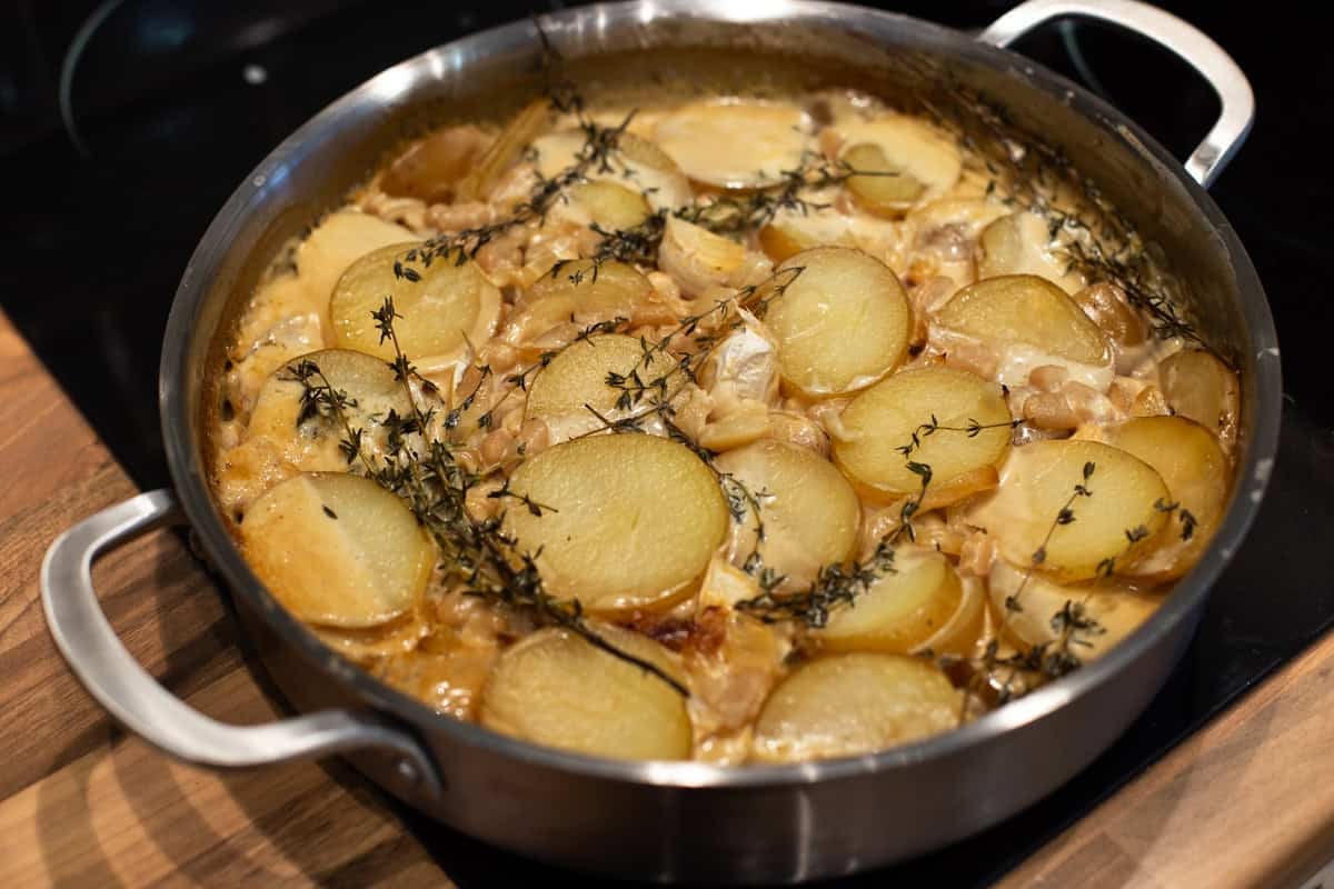 Cooked creamy potato bake in a metal pan.