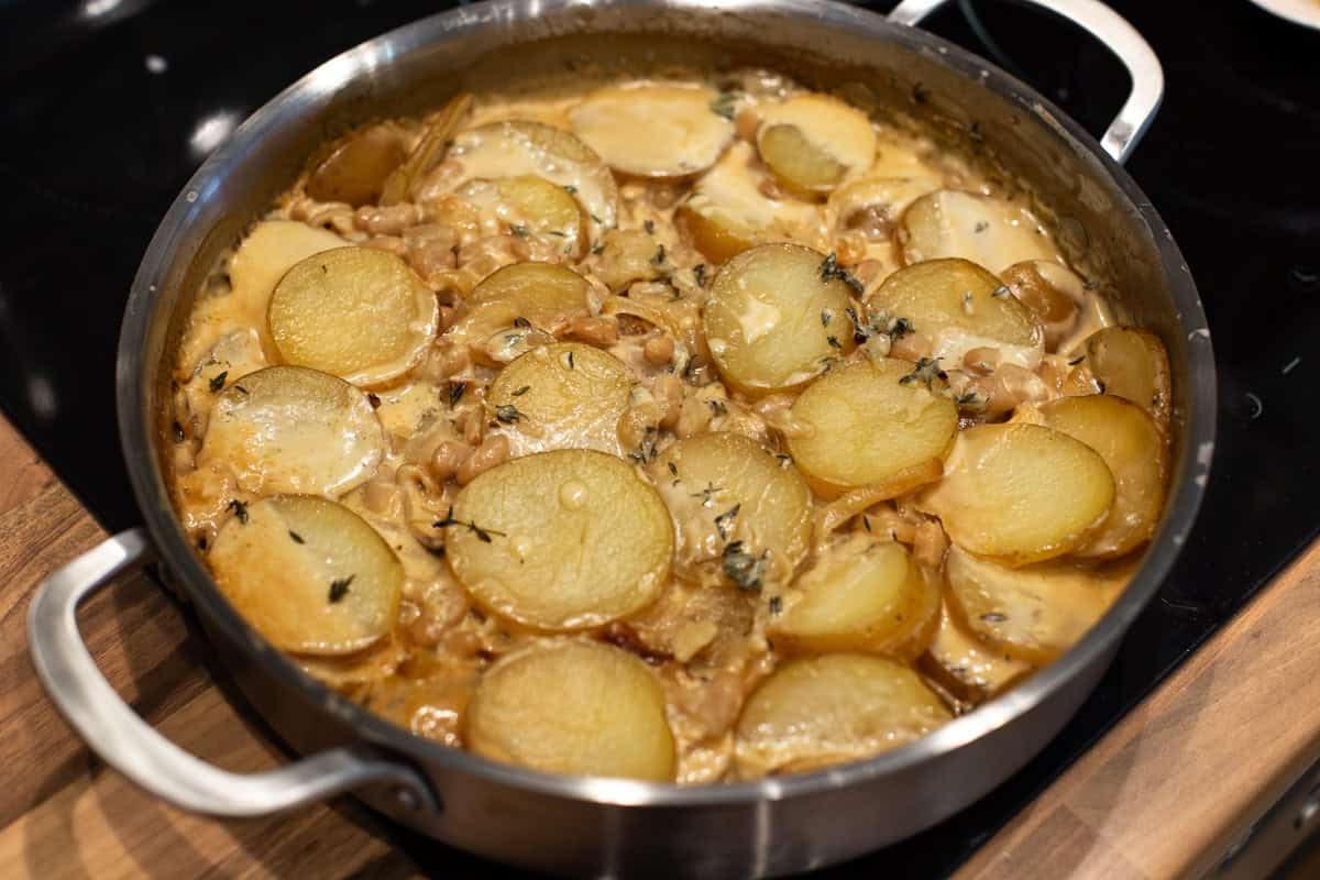 Cooked potatoes, beans and cream in a metal pan.